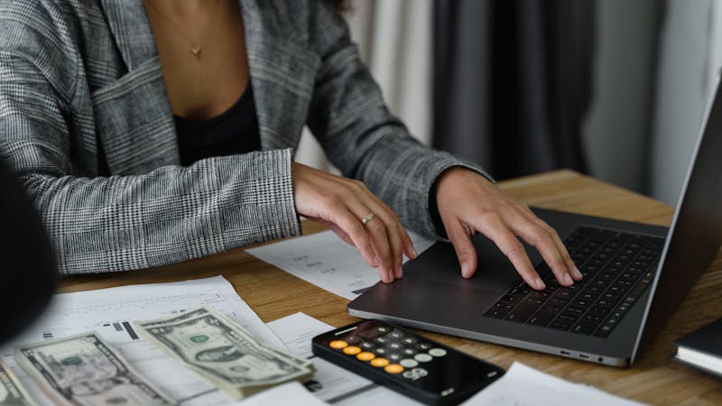 Person working on a laptop with financial documents and calculator, representing how offset accounts work alongside your mortgage