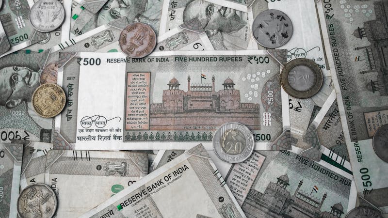 Indian rupee notes and coins spread out, representing where to safely park your emergency savings in India