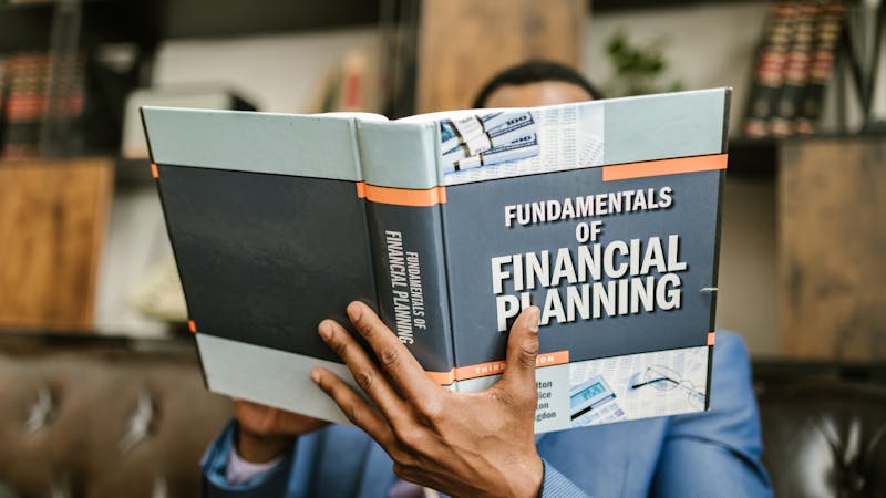 Person reading a financial planning book, representing the research needed to choose between fixed and variable rates