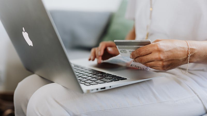 Person shopping online with a credit card and laptop, representing conscious spending decisions