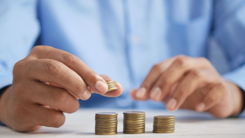 Person carefully stacking gold coins, representing taking control of daily spending habits